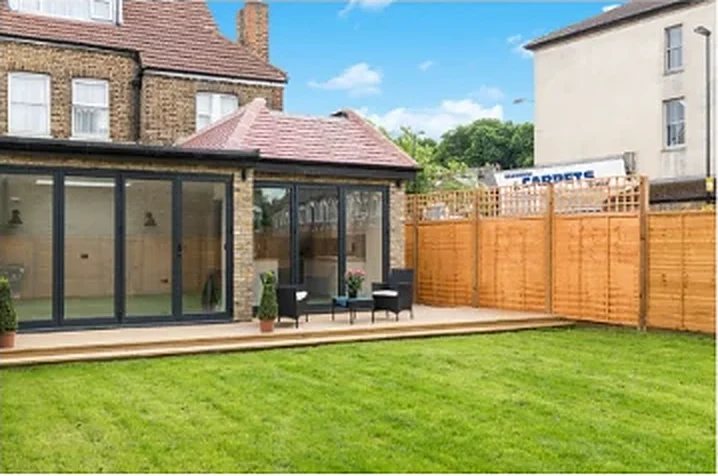 Single-storey rear extension with black-framed glazing and a garden deck at Stondon Park Road, London